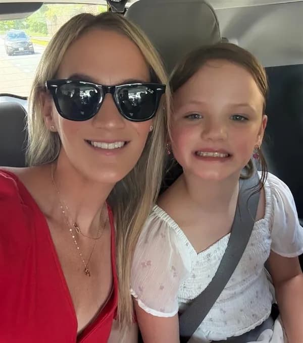 Woman wearing sunglasses and a girl smiling together in a car.